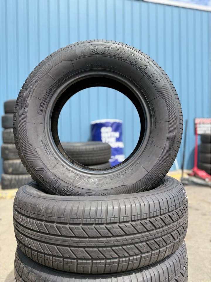 Stack of used tires at Universal Tire Tire Center in front of blue wall.