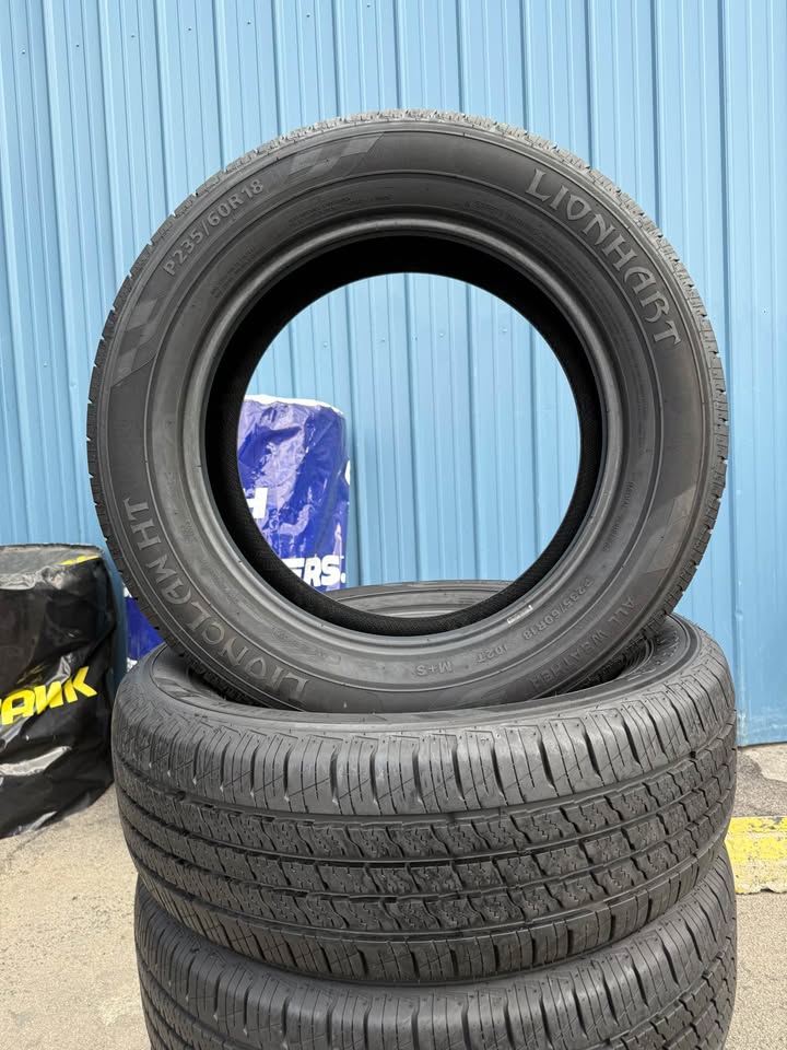 Stack of used tires outside Universal Tire Tire Center with blue wall background.
