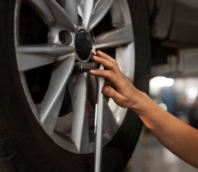 Technician changing a car tire with a wrench at Value Tires & Service.