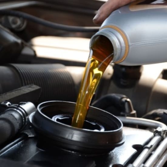 Engine oil being poured into a car engine during maintenance.