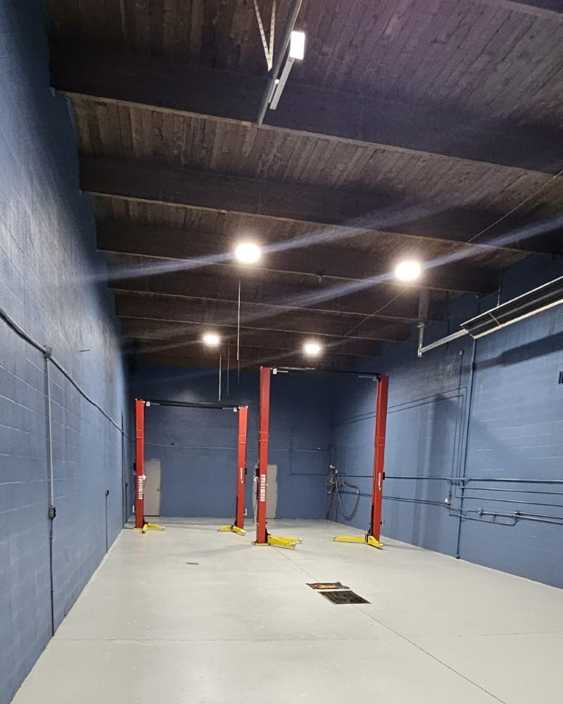 Car service lift in an auto workshop with blue walls and ceiling, four red hydraulic lifts for vehic.