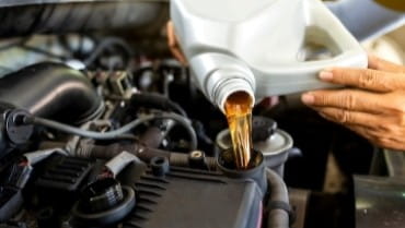 Engine oil being poured into a car engine during maintenance at Vroom Auto.