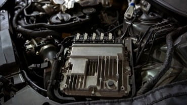 Close-up of car engine control module in vehicle engine bay.