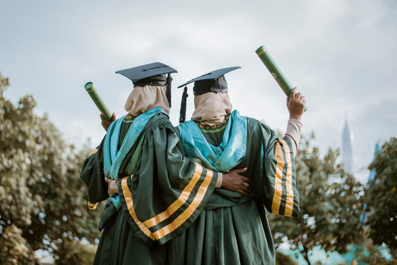 Two graduates celebrating achievement outdoors in Maldives.
