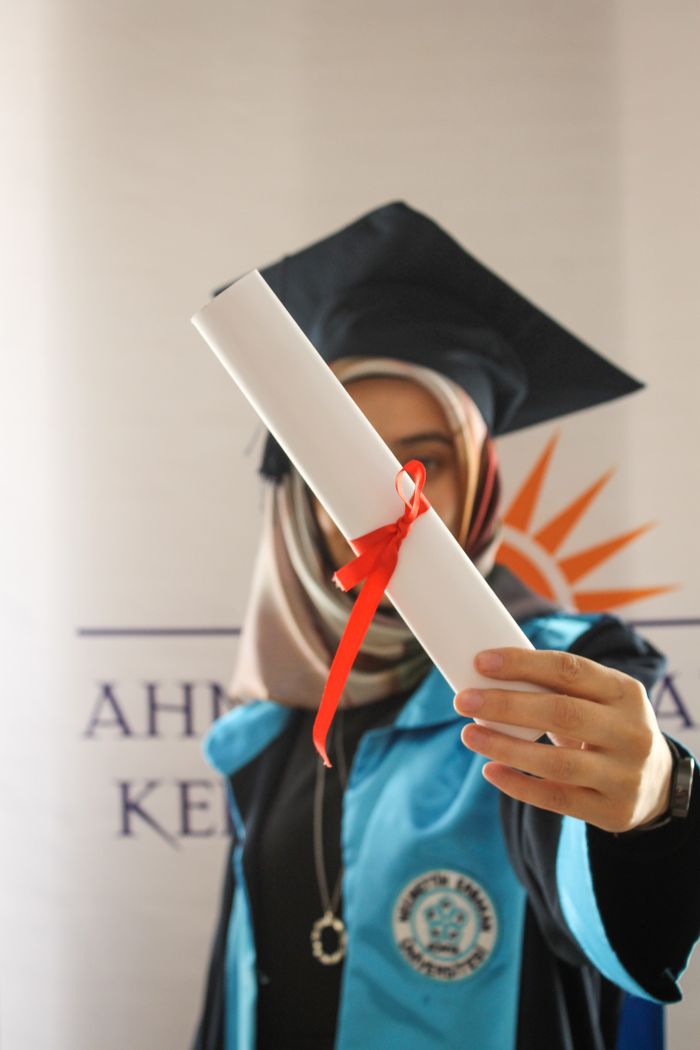 Woman in graduation gown holding diploma, celebrating academic achievement.