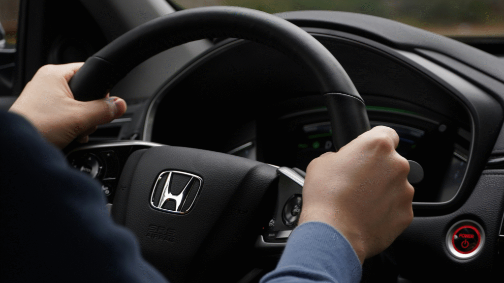 Close-up of a person holding a Honda steering wheel inside a vehicle at Wallace Automotive.