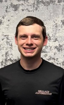 Auto repair technician smiling in workshop, professional automotive service.