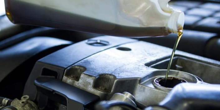 Automotive engine oil being poured during vehicle maintenance at Wallace Automotive.