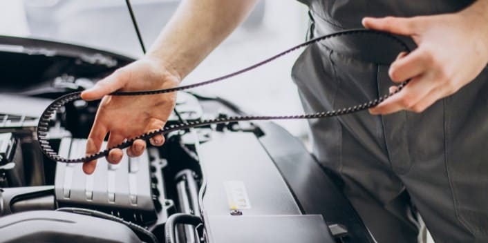 Technician inspecting car engine during maintenance at Wallace Automotive.