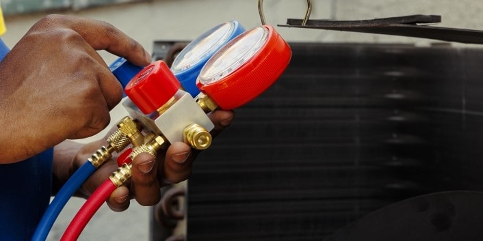 Technician checking car AC pressure gauges.