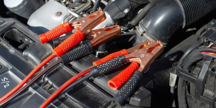 Car battery cables with red and black insulation, connected to a vehicle's battery for optimal power.