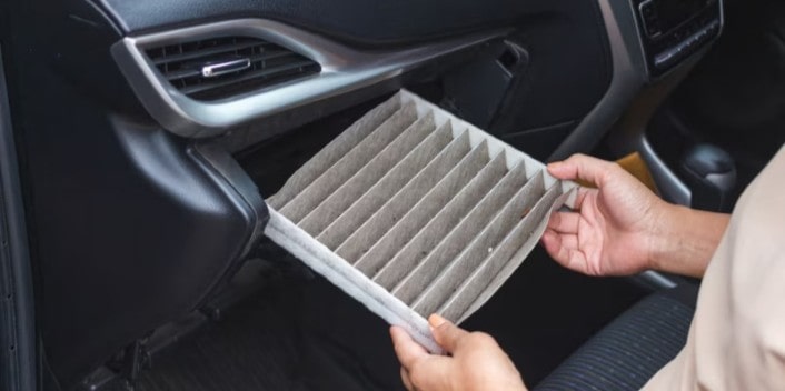 Air filter being replaced inside a car for optimal engine performance.