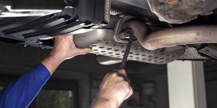 Skilled mechanic inspecting underside of vehicle for maintenance or repairs.
