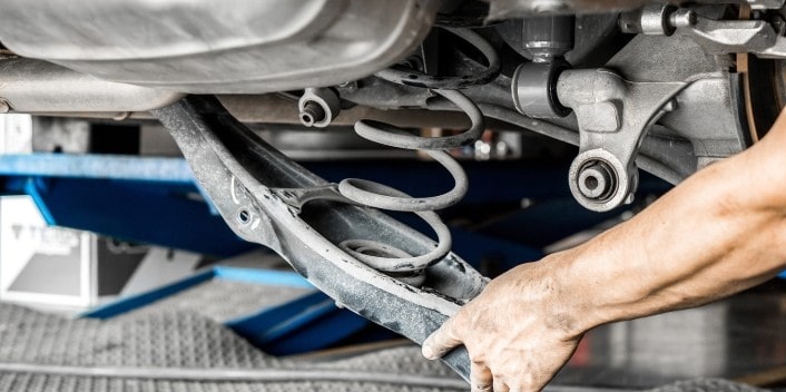 Mechanic inspecting vehicle suspension system during auto repair service.