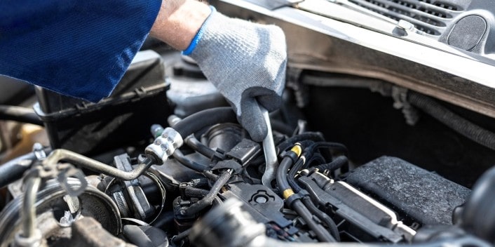 Engine repair technician inspecting car engine components.