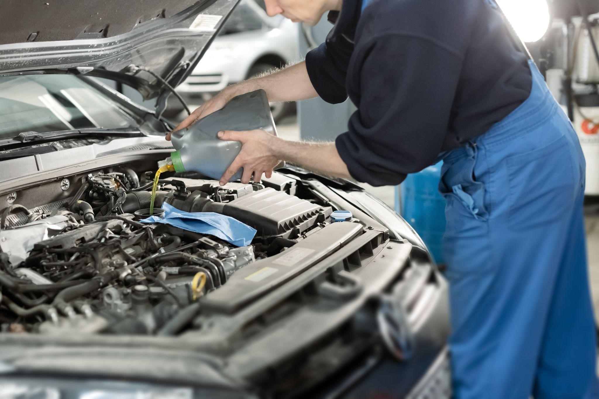 Automotive technician performing engine oil change on a vehicle at Wallace Automotive.
