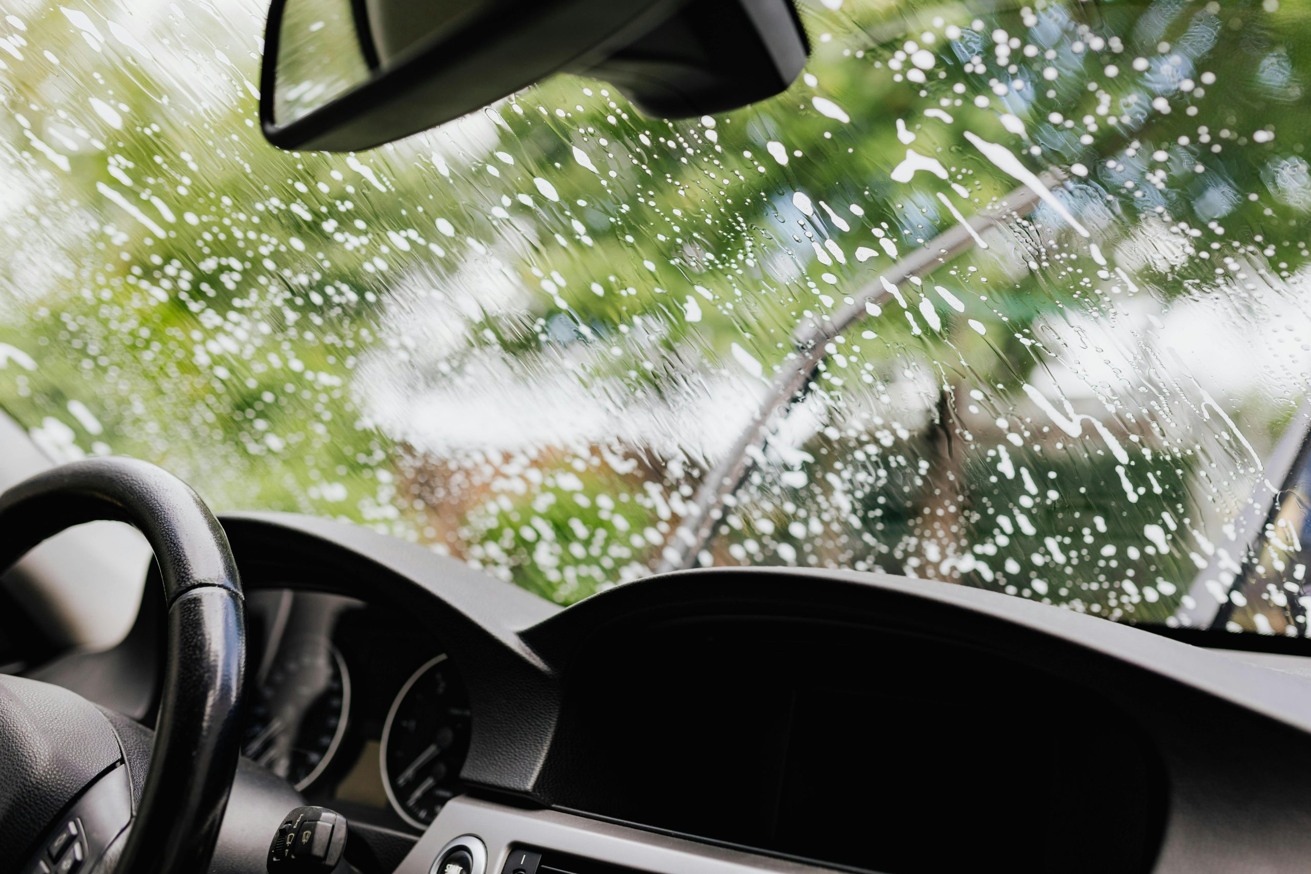 Rainy windshield with wipers in motion at Wallace Automotive, expert auto repair and maintenance ser.