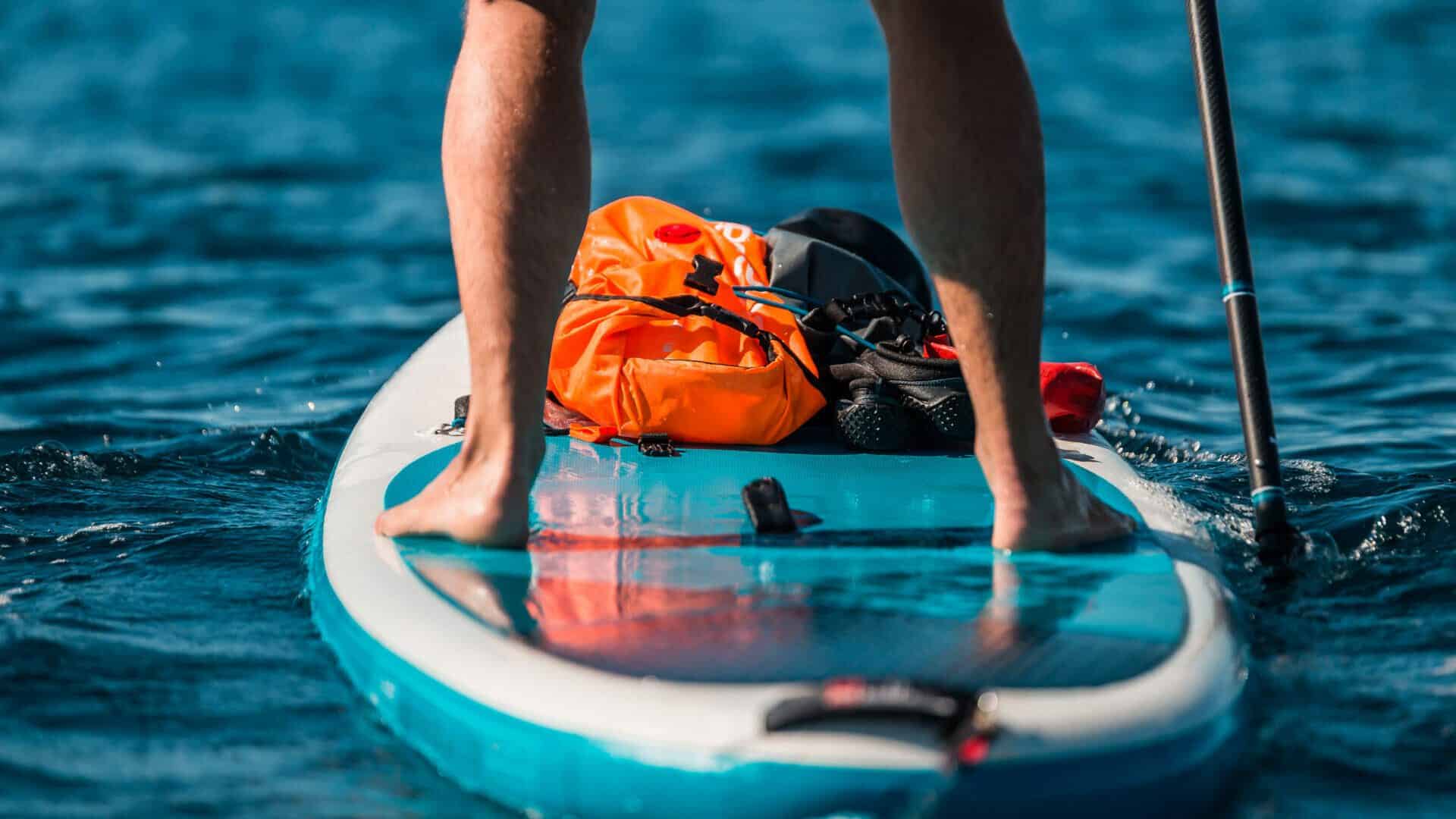 Young athletic man paddling on a SUP stand up paddle board in bl