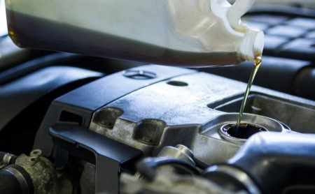 Oil being poured into a car engine during maintenance.