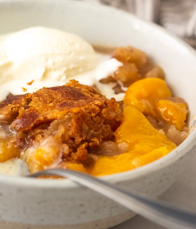 a bowl of southern peach cobbler with ice cream