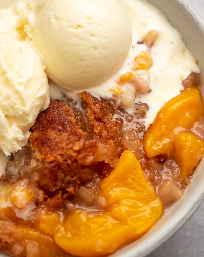 A bowl of ice cream with buttery crisp topping peach cobbler