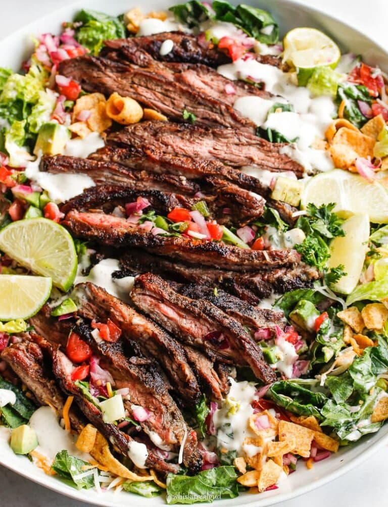 A bowl of salad with taco seasoned steak and cilantro lime dressing topped with fritos