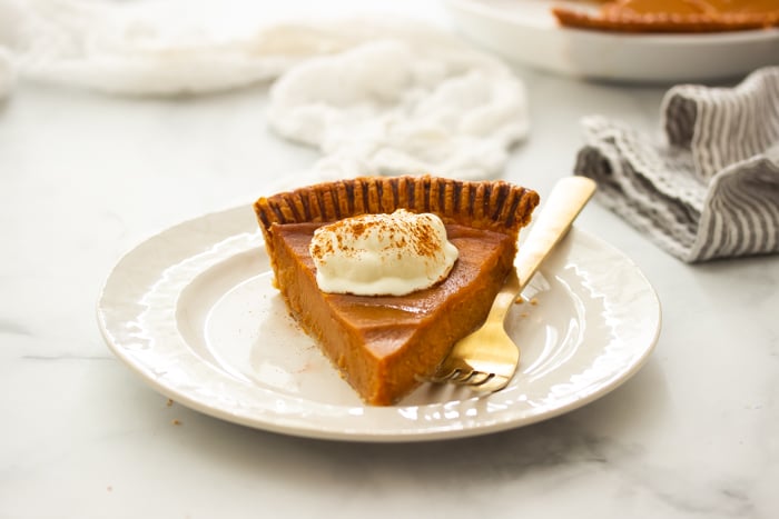 southern sweet potato pie on a plate topped with whipped cream. 