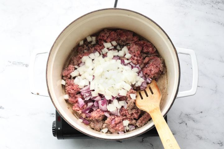 A picture of ground beef in a dutch oven with onions