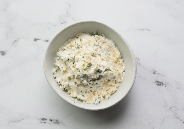 A picture of ricotta cheese in a bowl with parsley mozzarella cheese and parmesan 