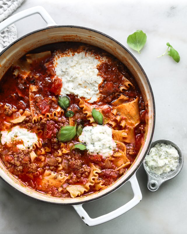A picture of lasagna soup in a pot topped with ricotta cheese 