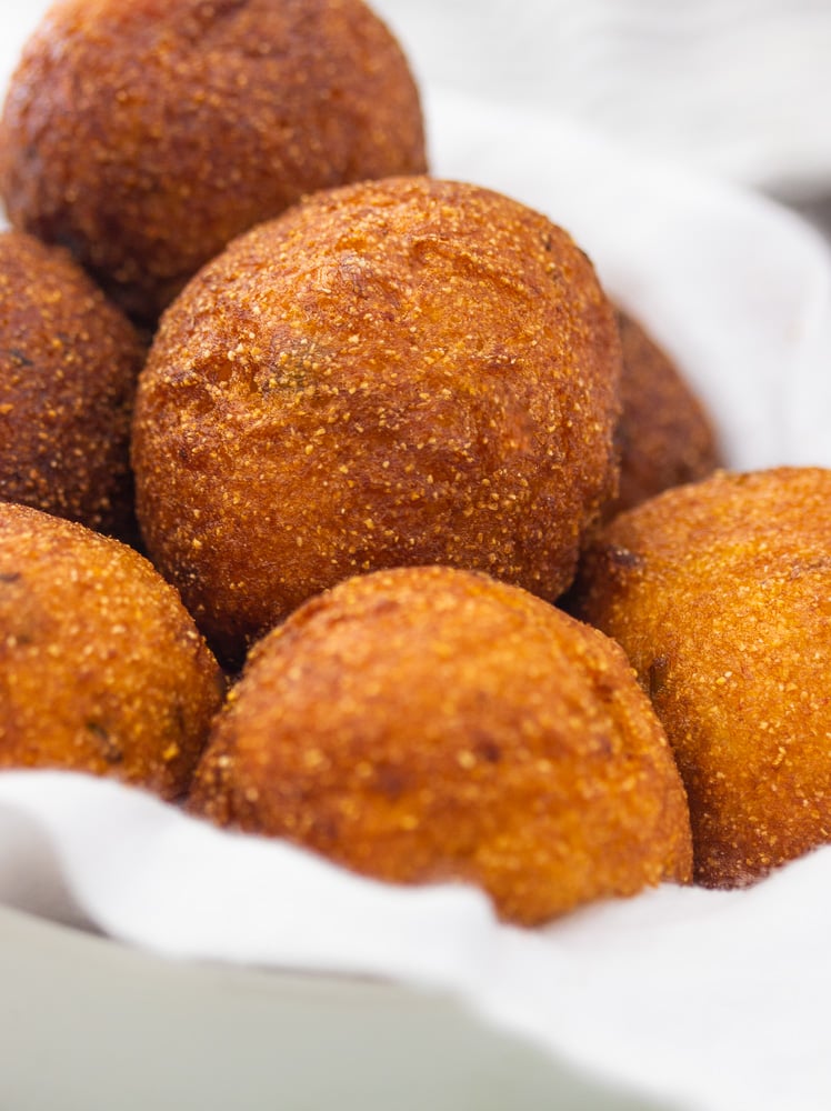 a bowl of golden brown round hush puppies