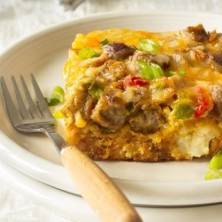 A tater tot breakfast casserole with crispy tater tots, eggs, melted cheese, sausages, peppers and onions.