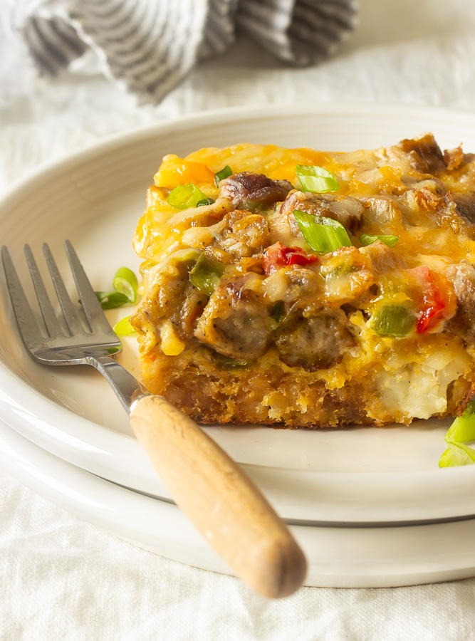 A tater tot breakfast casserole with crispy tater tots, eggs, melted cheese, sausages, peppers and onions.