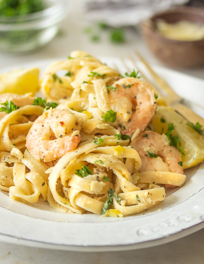 A plate of lemon garlic parmesan shrimp pasta with zested lemon and parmesan cheese