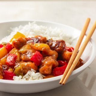 A bowl of sweet and sour chicken over rice