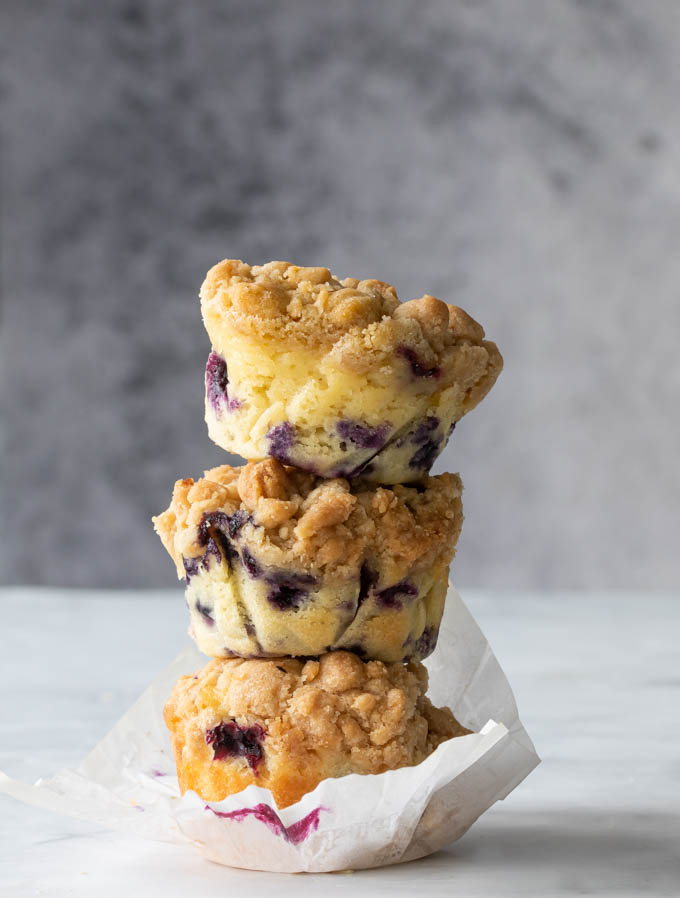 3 old fashioned blueberry muffins stacked on top of one another