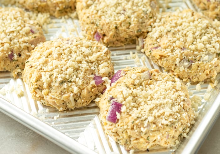 Crispy uncooked tuna cakes being prepped on a baking sheet