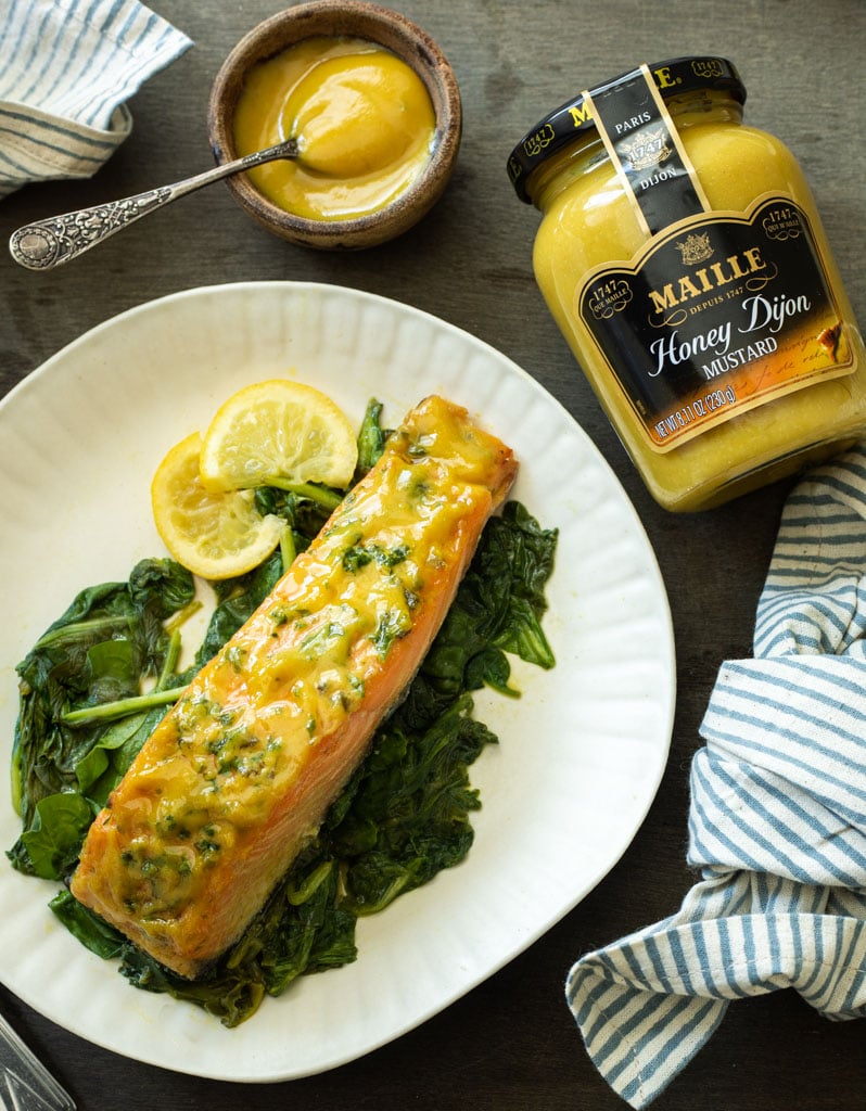 A picture of a plate of honey mustard salmon that's been roasted with spinach 