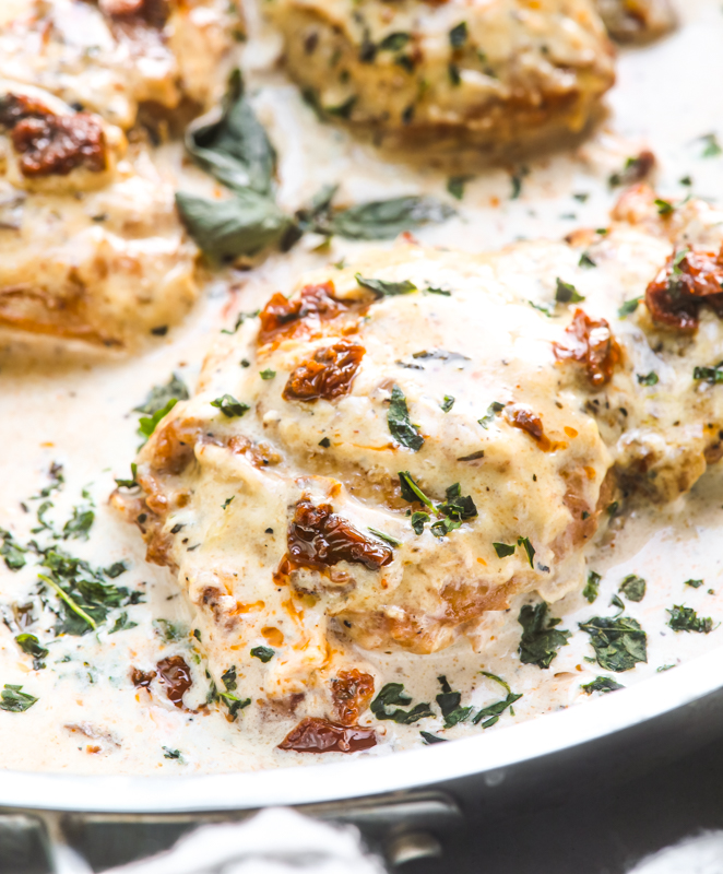 A picture of creamy chicken thighs in a basil cream sauce in a skillet