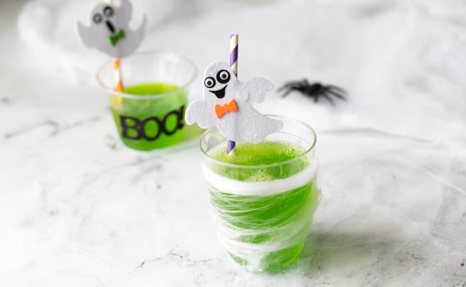 Green Halloween drink in a halloween decorated cup.