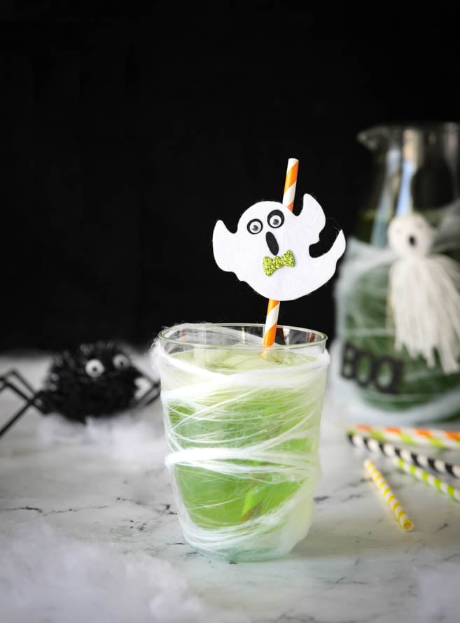 A green halloween drink decorated with halloween decor.