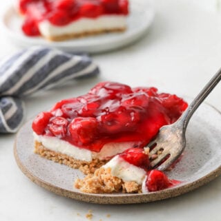A picture of cherry delight dessert with cherry topping on a plate