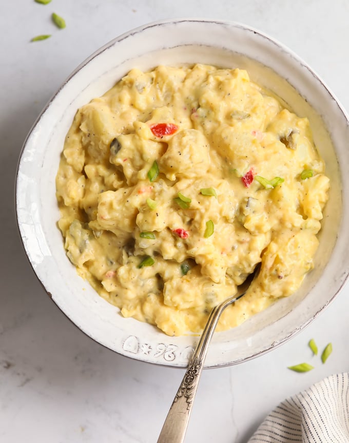 A picture of a bowl of soul food potato salad with eggs and yellow mustard