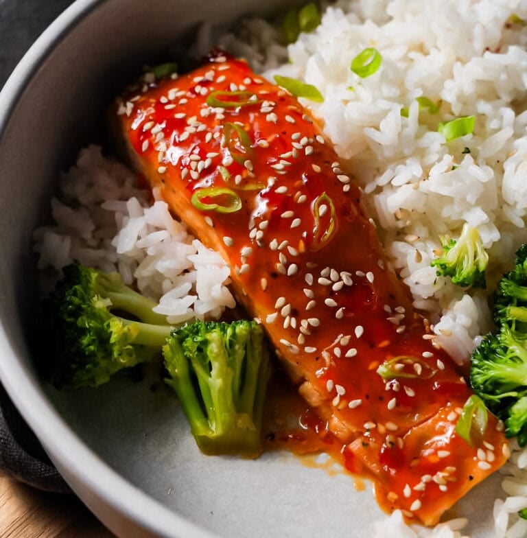 Sweet chili salmon fillet baked until tender, glazed with sticky sweet chili sauce, and garnished with sesame seeds and green onions.