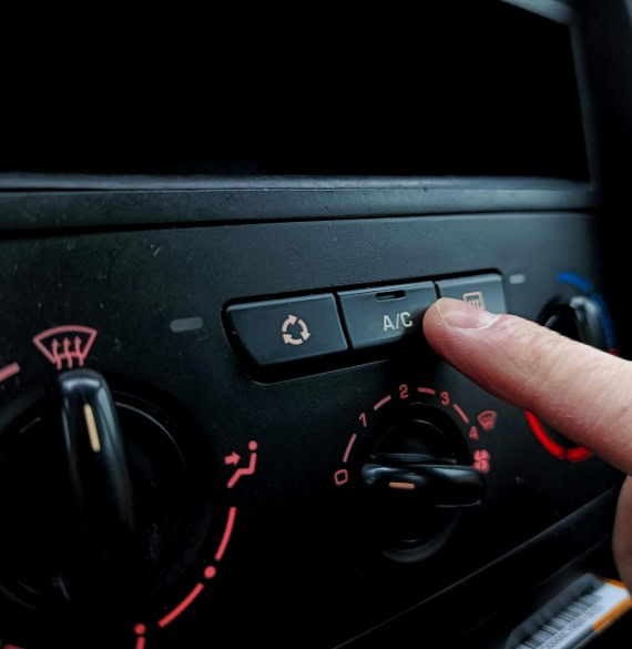 Close-up of climate control panel with a finger adjusting the temperature setting.