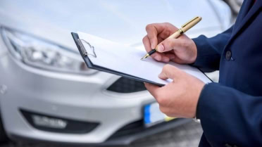 Technician inspecting a car with a clipboard at Winston Wheels & Tires.