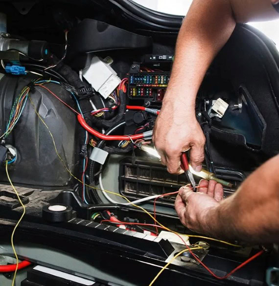 Automotive technician working on car wiring and electrical system repair at Winston Wheels & Tires.