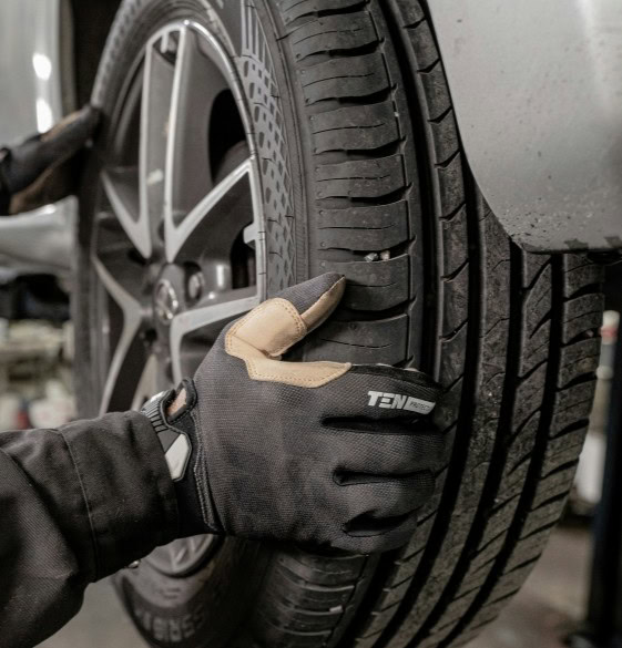 Close-up of a hand inspecting a car tire at Winston Wheels & Tires.