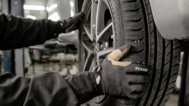 Technician inspecting a car tire at Winston Wheels & Tires shop.