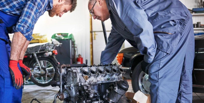 Engine repair workshop with two mechanics working on an engine.